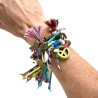 Pulsera de Gamuza con dijes de diferentes metales, flecos, muñequitas y flores